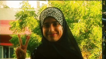 Example: a young woman in Karachi raising a peace sign, with trees behind her